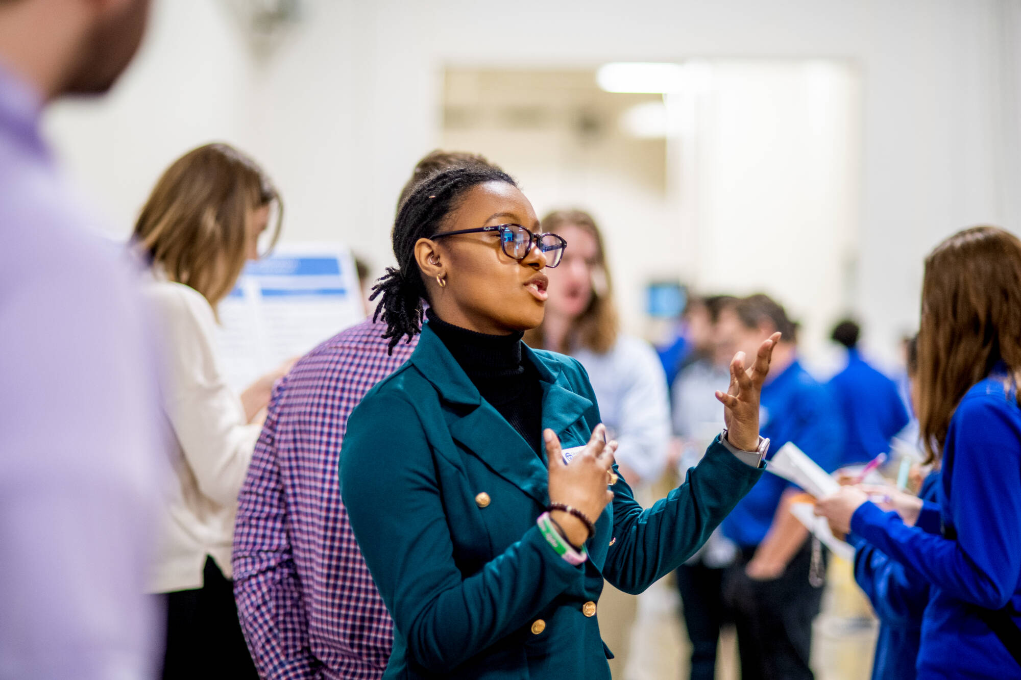 Person wearing blue jacket speaking to poster conference participants